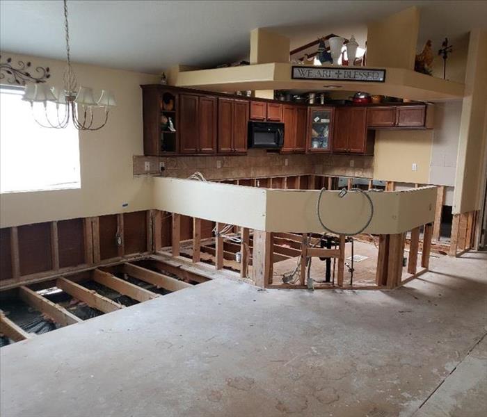 A open room with a kitchen missing the lower cabinets, drywall and flooring. 